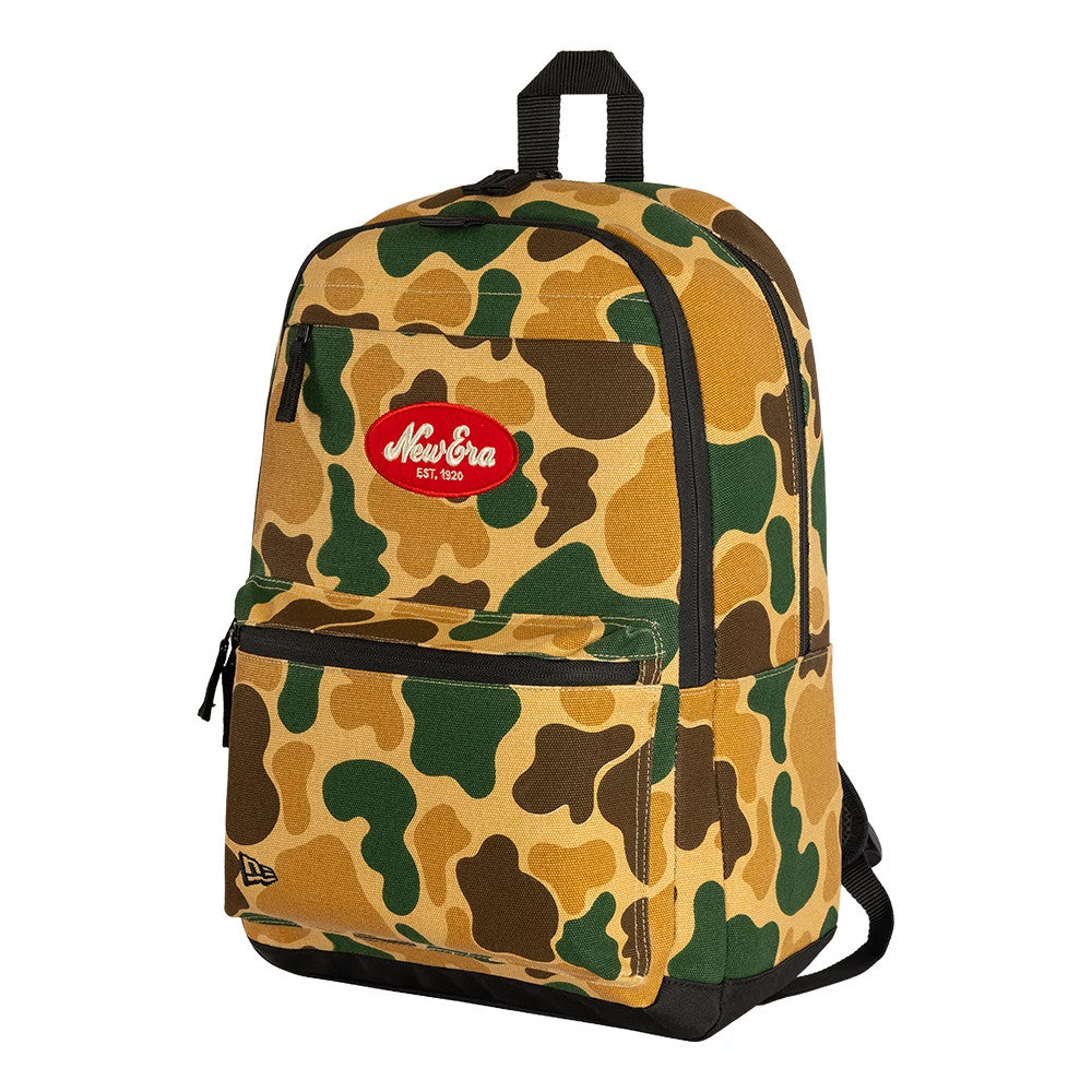 New Era Camo Light Beige Delaware Backpack, three-quarter view showing the brown and green camouflage pattern, a red embroidered New Era logo on the upper front, a zipped front pocket and a black loop handle on the top.
