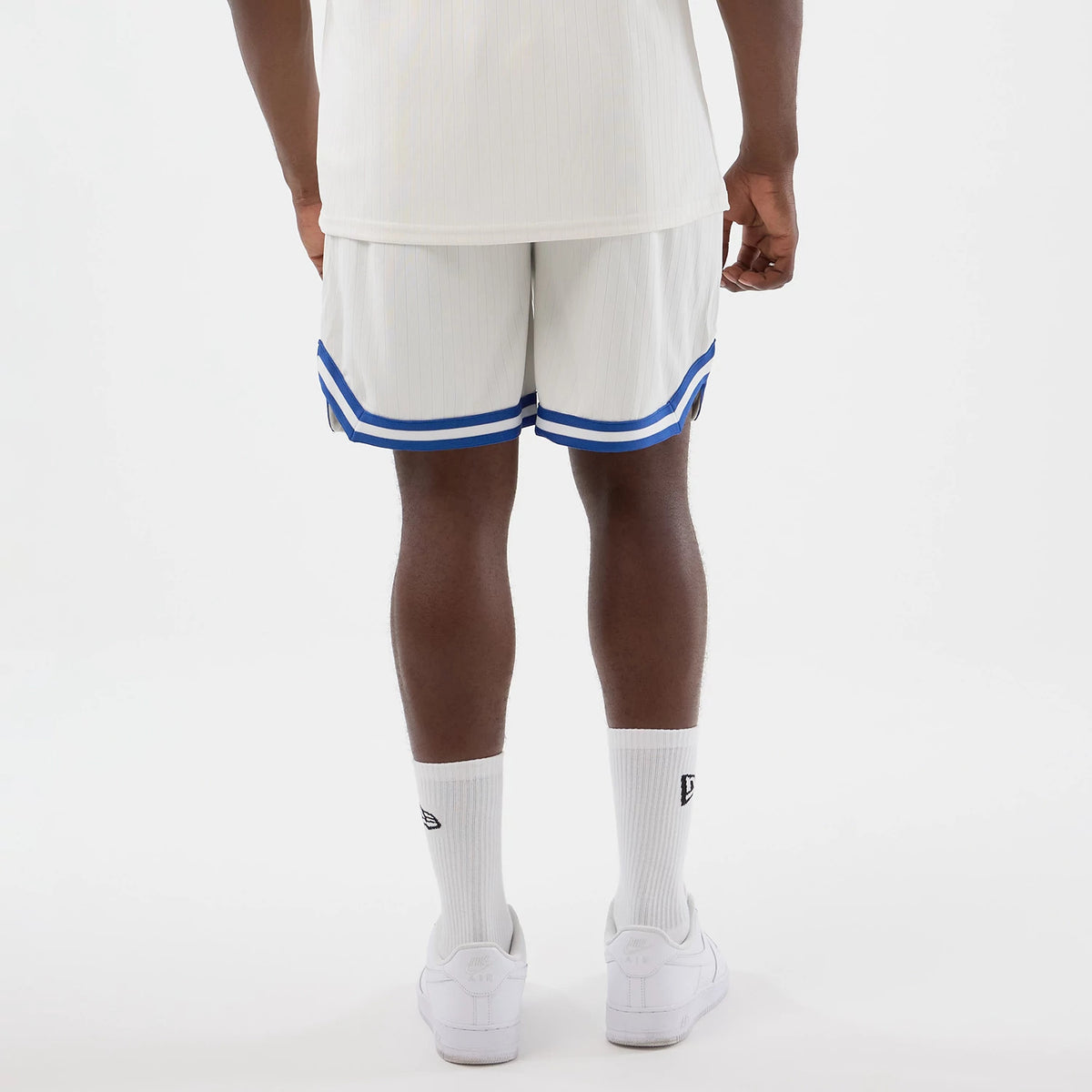 New Era LA Dodgers MLB Arch Open White Oversized Shorts, back view on a model, showing the white fabric with dual blue stripes along the hem, a relaxed silhouette, and a pinstripe pattern throughout.
