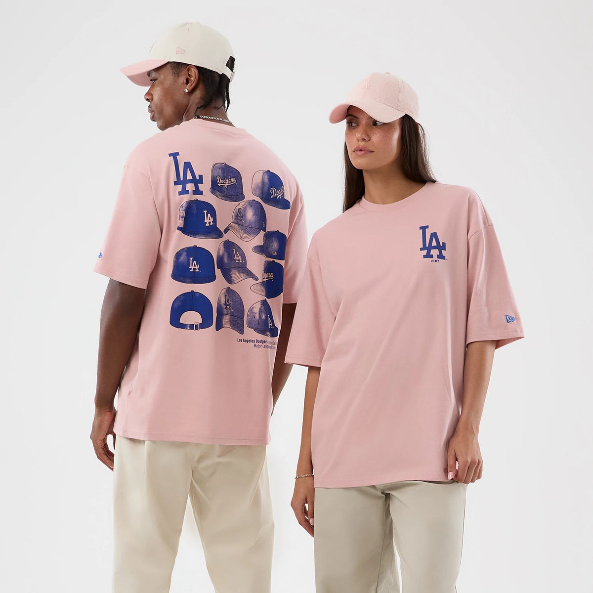 New Era LA Dodgers MLB Cap Graphic Pastel Pink Oversized T-Shirt, front and back view on models showcasing a large blue LA logo on the chest, multiple cap graphics with logos in blue on the back, and a blue embroidered New Era logo on the sleeve.