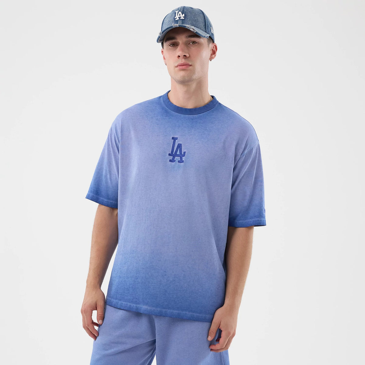 New Era LA Dodgers MLB Washed Logo Pastel Blue T-Shirt, front view on-model showing the faded blue gradient across the shirt and an embroidered LA logo centred on the chest, styled with matching blue shorts and a coordinating pastel cap.