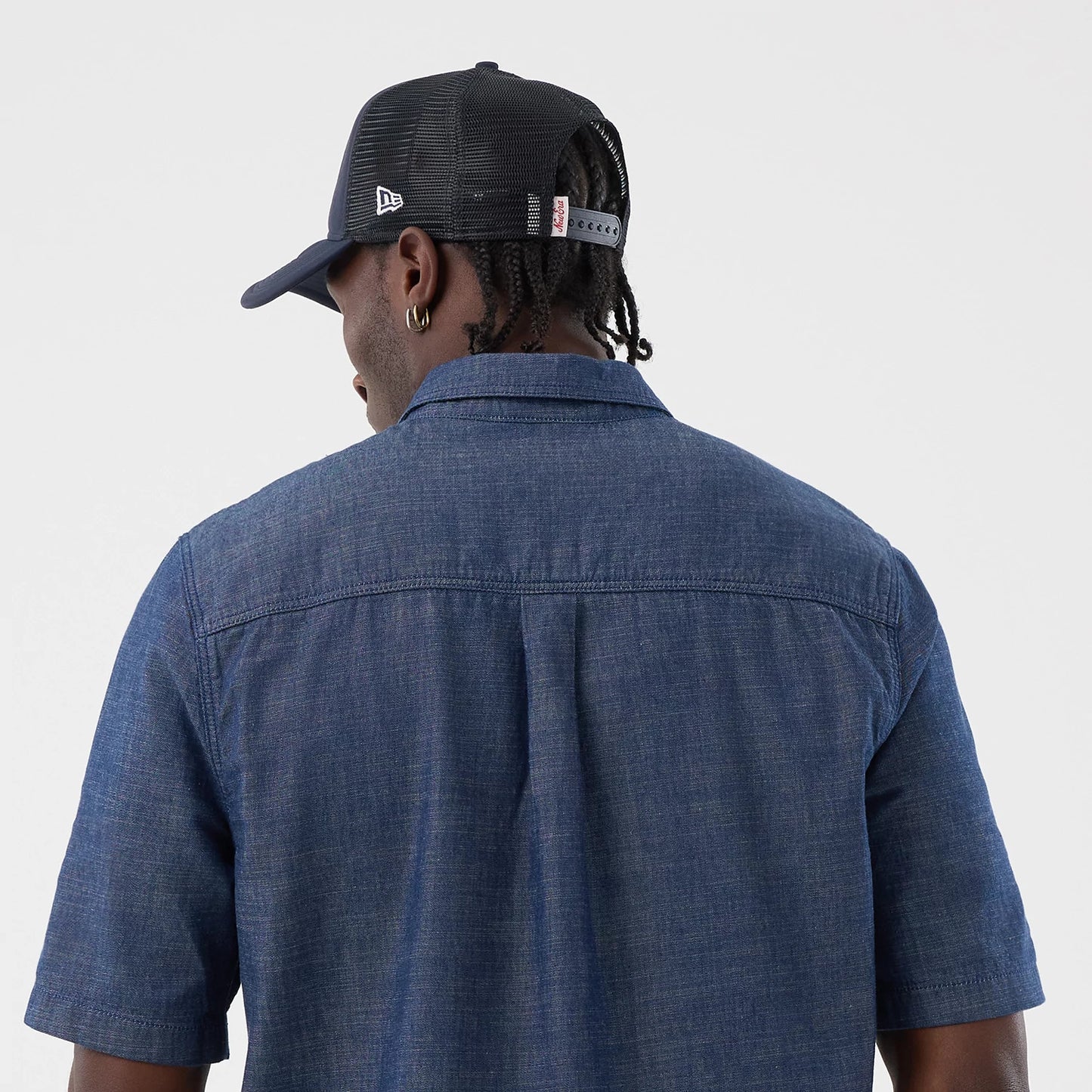 The model is wearing this New Era Denim Short Sleeve Shirt in blue. 7