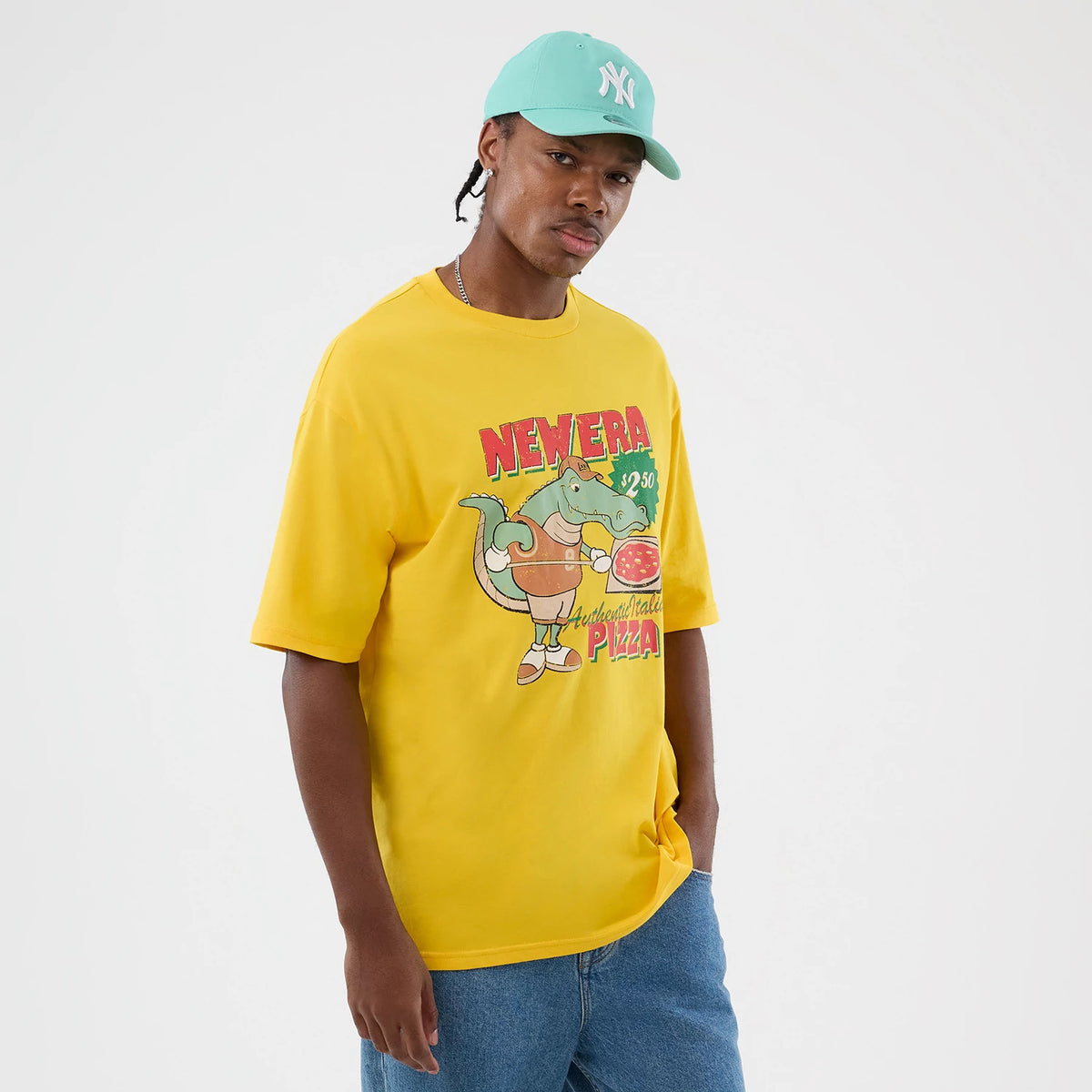 New Era Alligator Character Graphic Yellow T-Shirt, front view on-model featuring a bright yellow fabric with a colourful, whimsical alligator graphic holding a pizza and large Nevera Authentic Pizza text across the chest, styled with casual jeans.