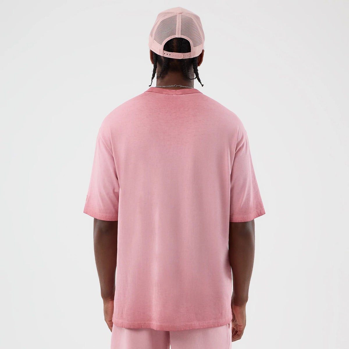 New Era New York Yankees MLB Washed Logo Pastel Pink T-Shirt, back view on a model with a matching pastel pink cap, showcasing a plain design with a relaxed fit, short sleeves, and a round neckline, accentuating the shirt's soft pink hue.