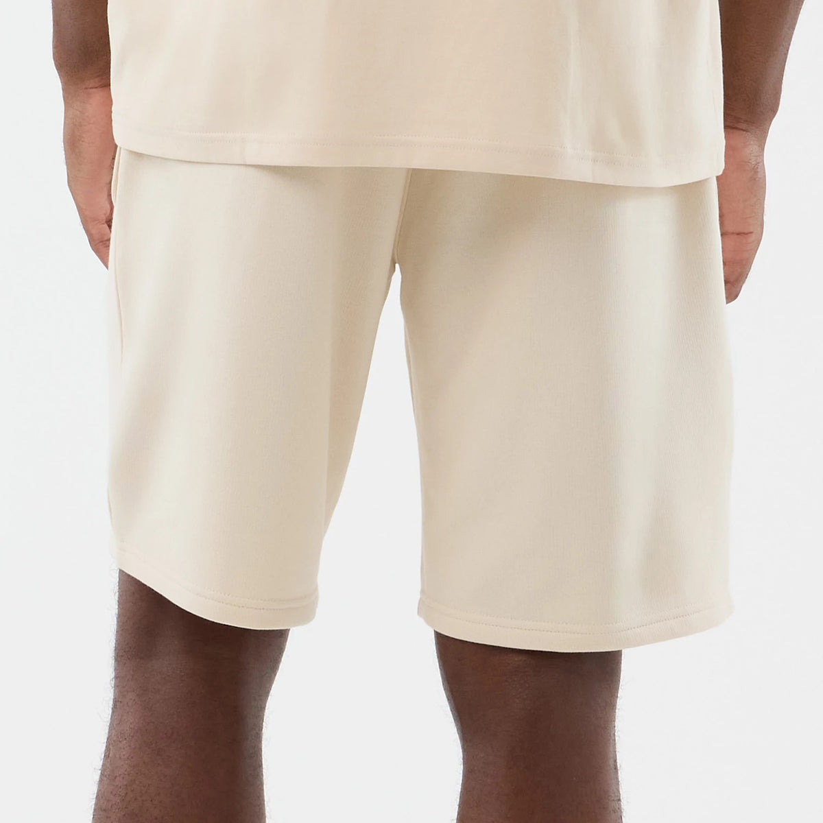 New Era Chicago Bulls NBA Core Plus Light Beige Shorts, back view on a model showcasing a clean light beige finish, knee-length cut, and a relaxed fit, with plain back style and stitching around the hem.