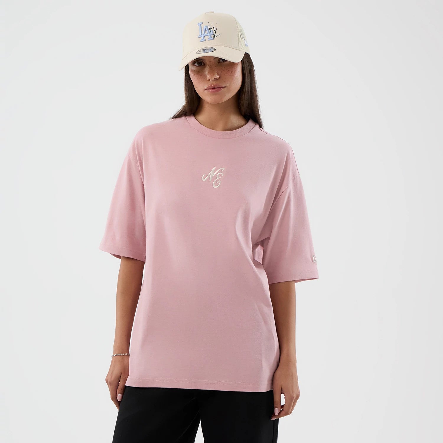 The model is wearing this New Era Floral Graphic Oversized T-Shirt in pastel pink. 4