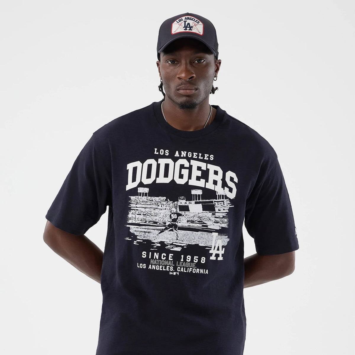 New Era LA Dodgers MLB Slub Navy Oversized T-Shirt, front view on-model showcasing white Dodgers lettering above a detailed stadium graphic with team emblem at the bottom right, worn with a coordinating cap featuring a Los Angeles patch.