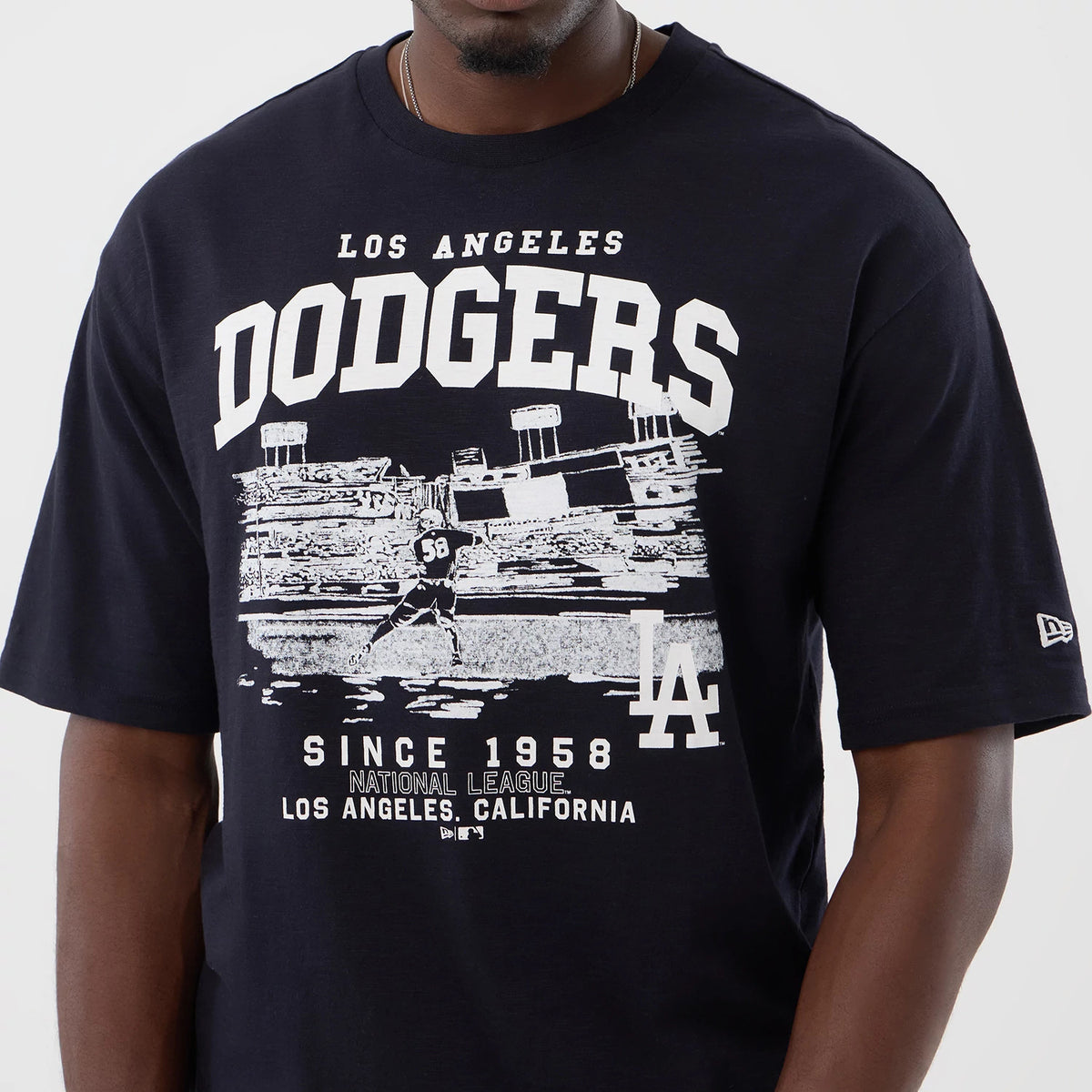 New Era LA Dodgers MLB Slub Navy Oversized T-Shirt, front view featuring large white DODGERS lettering across the chest above an image of a baseball player, LA logo printed at the bottom, and New Era flag embroidered on the left sleeve.