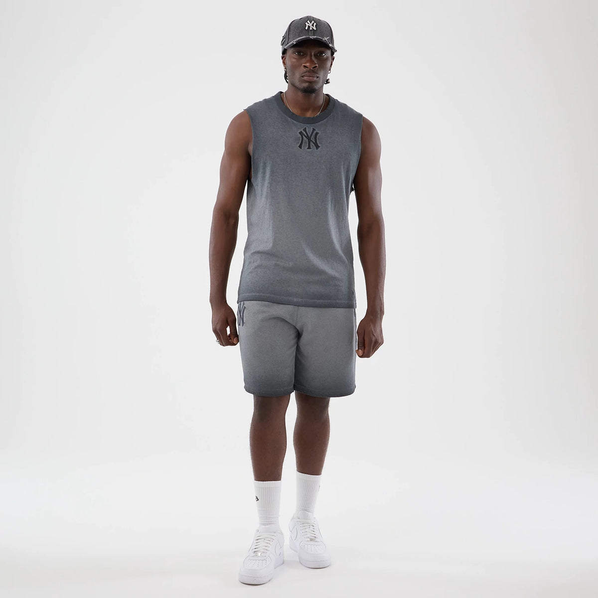 New Era New York Yankees MLB Washed Logo Black Vest, on-model view with a grey gradient design, featuring a dark embroidered Yankees logo on the front chest and sleeveless cut, paired with matching gradient shorts and white trainers.