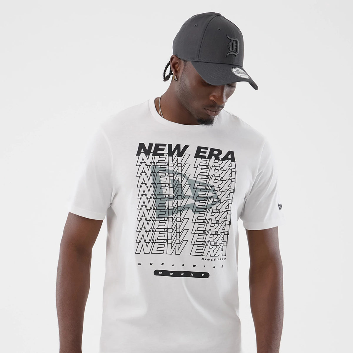 New Era Logo Graphic White T-Shirt, front view on-model with a layered text design featuring repeated New Era wording vertically down the front, distinctive contrasting black and grey letters, and an embroidered New Era flag logo on the left sleeve.