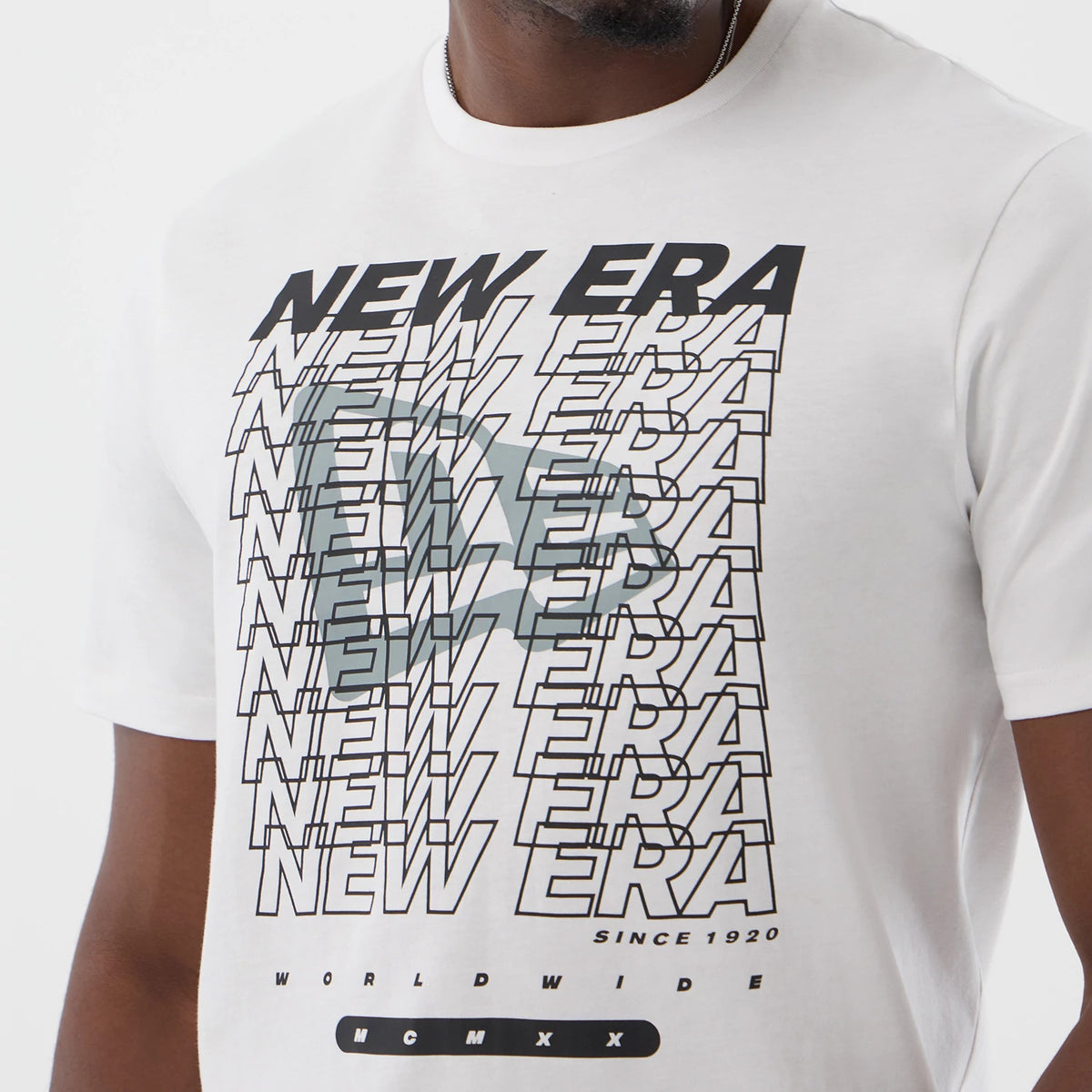 New Era Logo Graphic White T-Shirt, front view showing a repeating New Era text graphic in black and light grey overlapping across the chest, with small black lettering WORLDWIDE and Roman numerals MCMXX positioned below.