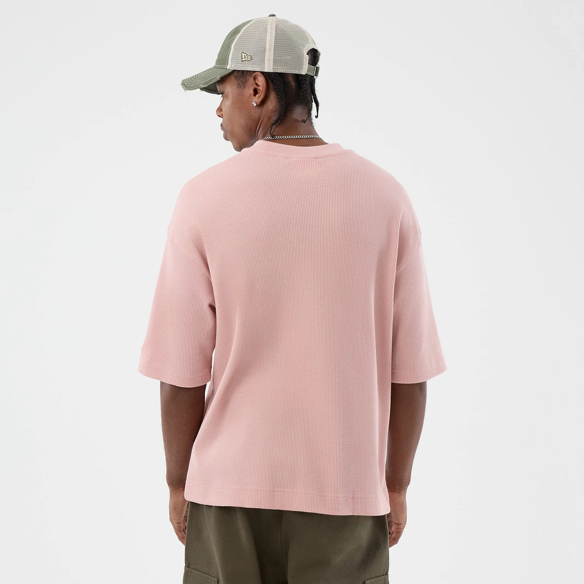 New Era Waffle Pastel Pink T-Shirt, back view on a model paired with an olive cap, showcasing a relaxed fit with elbow-length sleeves and a soft waffle texture, highlighting the simplicity and casual look from the rear angle.
