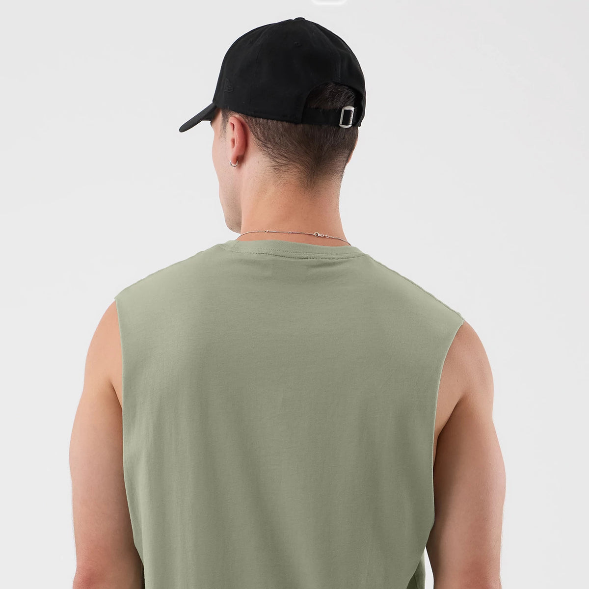 New Era Chicago Bulls NBA League Essential Pastel Green Vest, rear view on a model wearing a black cap, showcasing the sleeveless design and relaxed fit, with a straight hemline and a pastel green fabric enhancing the overall casual aesthetic.