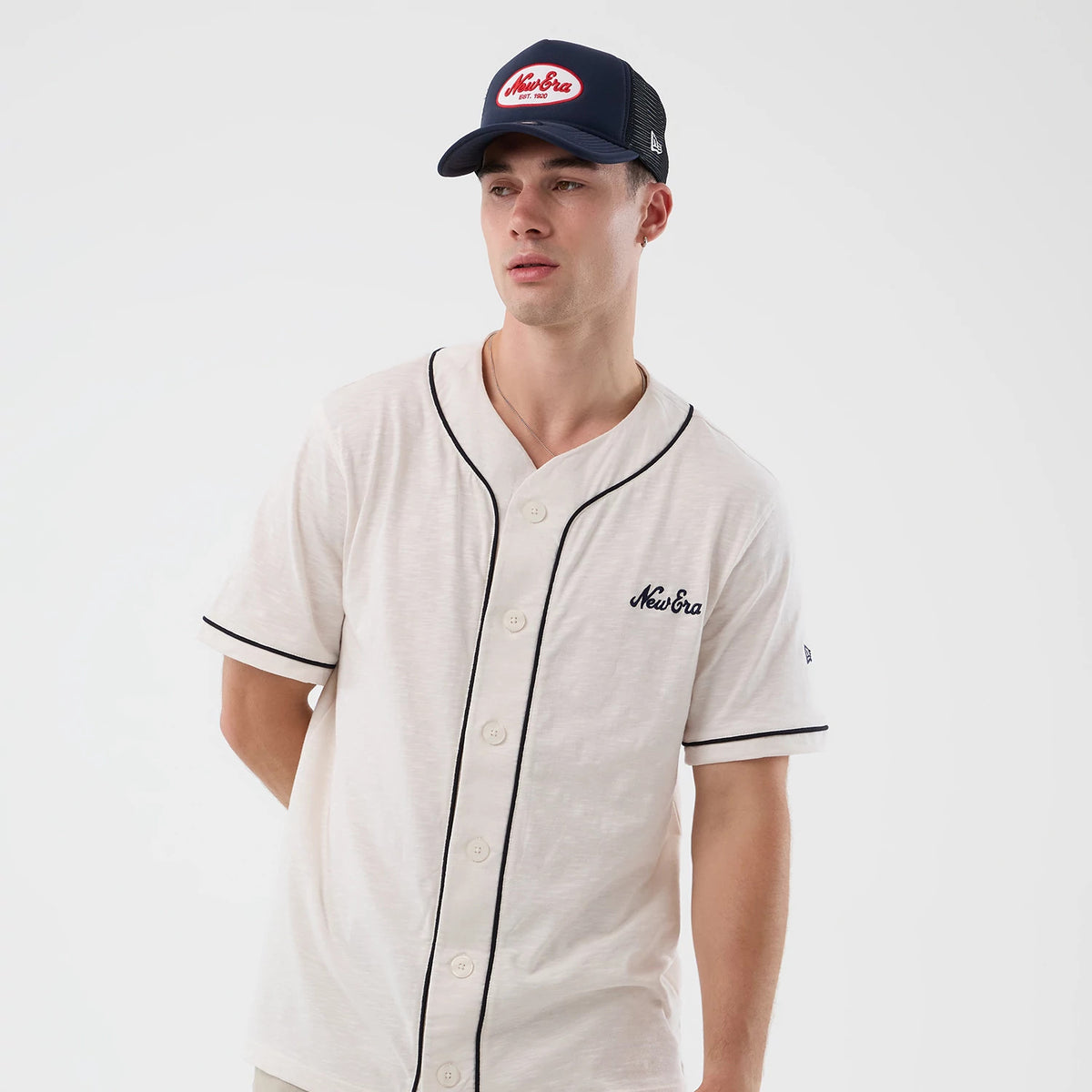 New Era Slub Open White Baseball Jersey, on-model front view with black piping along the button placket and sleeves, featuring an embroidered New Era logo on the left chest and a texture throughout the white fabric.