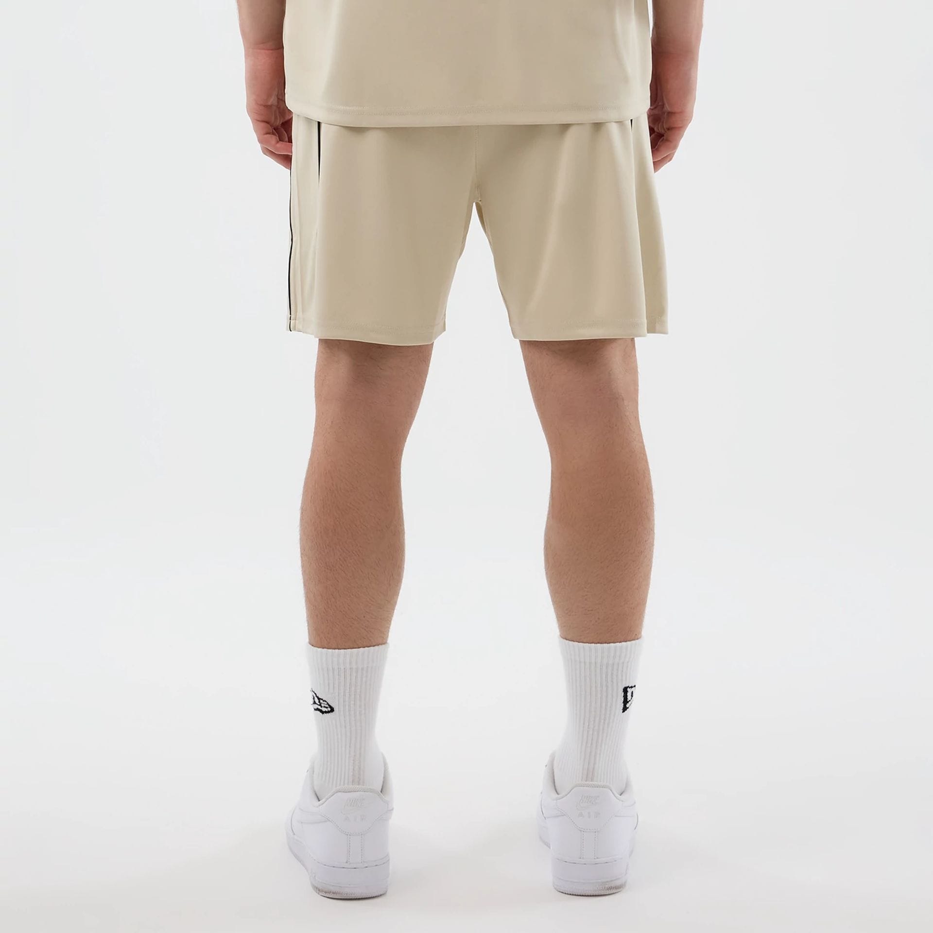 The model is wearing these New Era Football Shorts in light beige. 2