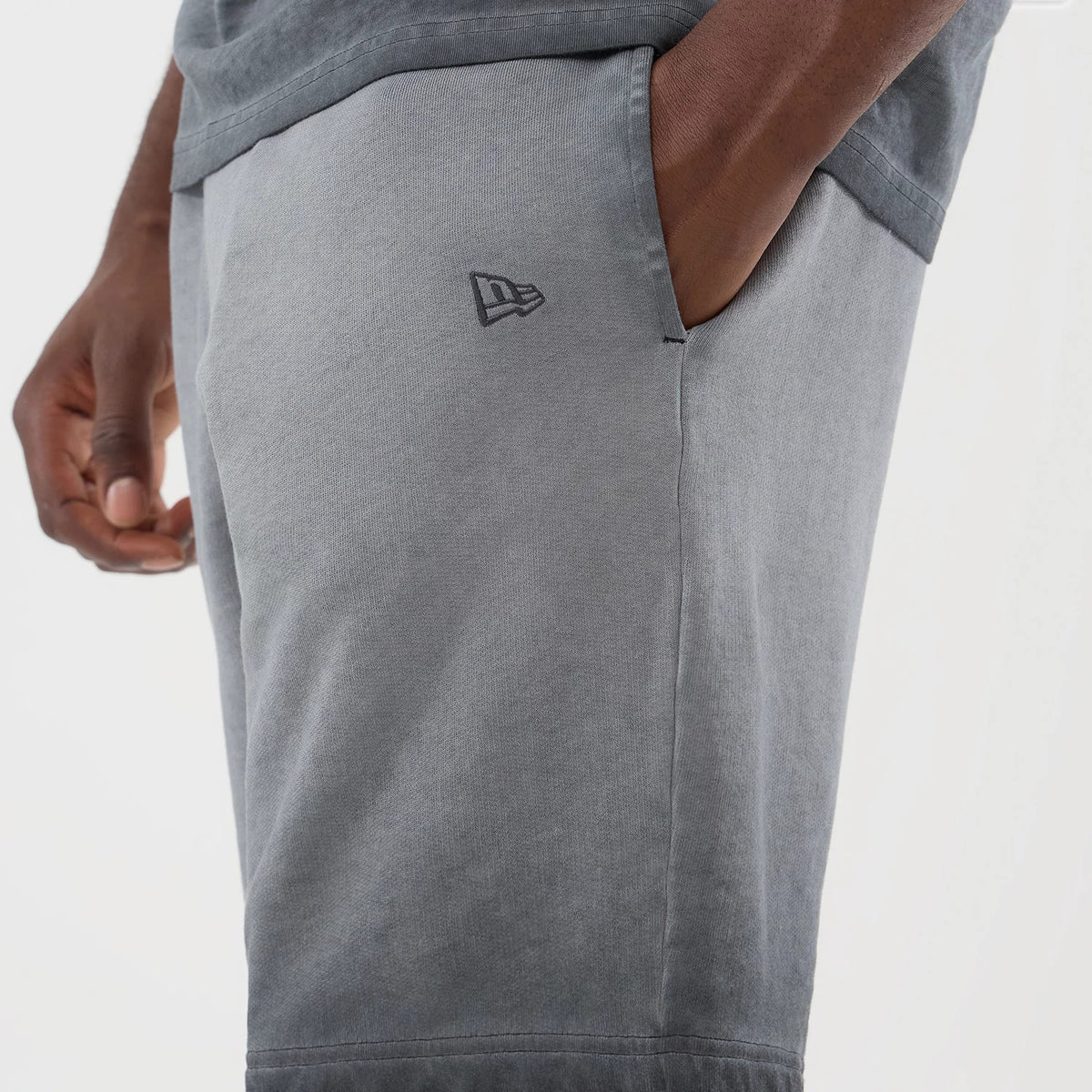 New Era New York Yankees MLB Washed Logo Black Shorts, side view on-model highlighting the light grey colour, side pocket detail, and small printed New Era logo on the left thigh, styled casually with a matching grey top.