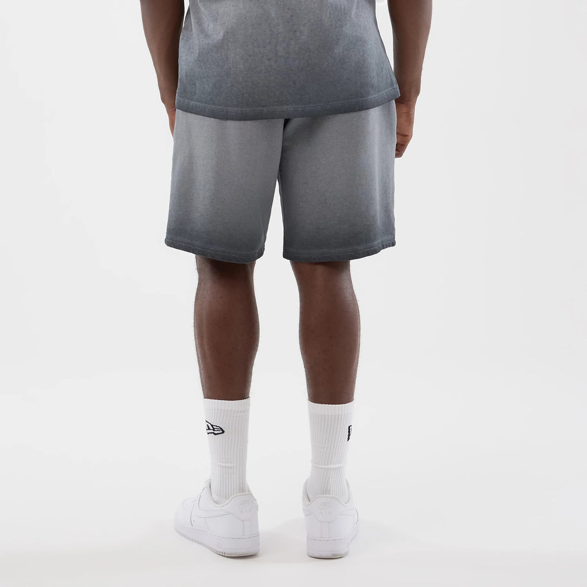 New Era New York Yankees MLB Washed Logo Black Shorts, back view on-model showing the faded black finish with a straight hem just above the knee, styled with white socks featuring an embroidered New Era logo above plain white sneakers.