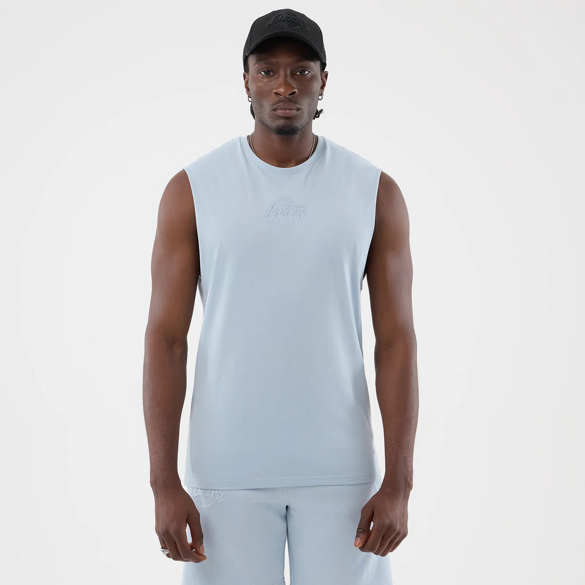 New Era LA Lakers NBA League Essential Pastel Blue Vest, front view on a model with a black cap, showing the team's embossed logo on the chest, a sleeveless design enhancing comfort, and a soft pastel colour.