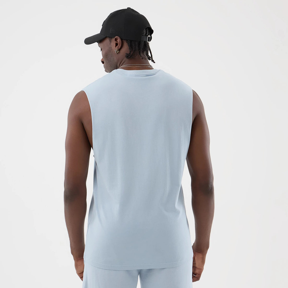 New Era LA Lakers NBA League Essential Pastel Blue Vest, back view on a model with a black cap, featuring a sleeveless design, relaxed fit, and crew neck, showcasing the light pastel blue fabric across the back and shoulders.