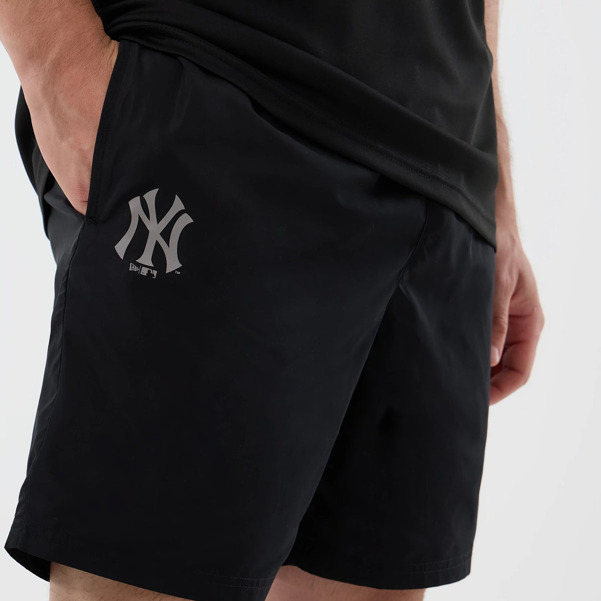 New Era New York Yankees MLB Core Plus Black Shorts, on-model view highlighting the grey printed New York Yankees logo on the left thigh, side pockets, and a relaxed fit, with the shorts styled casually with a matching black top.