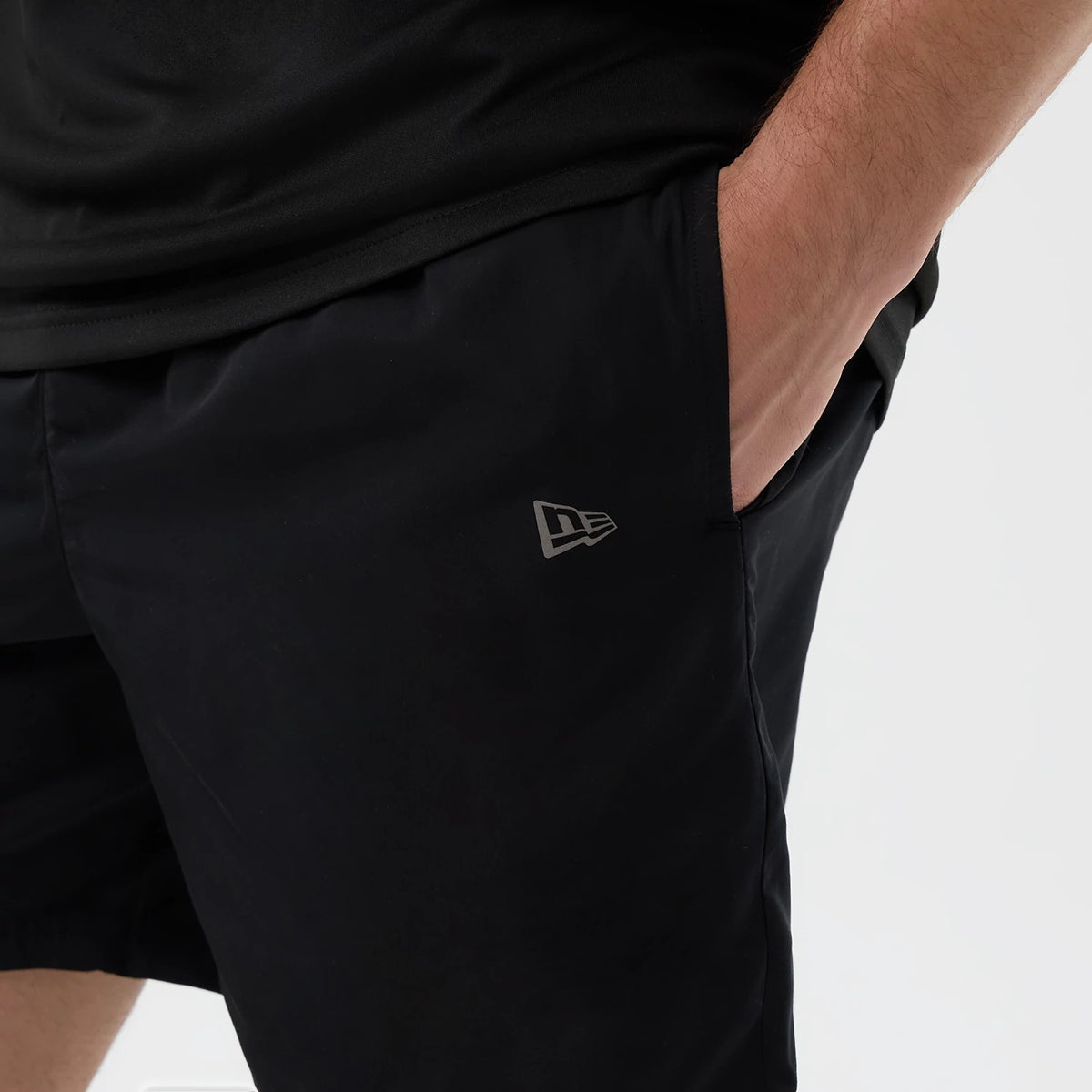 New Era New York Yankees MLB Core Plus Black Shorts, front view on a model showing the left hand resting in a side pocket, the shorts are black with a small grey embroidered New Era logo on the left thigh near the pocket edge.