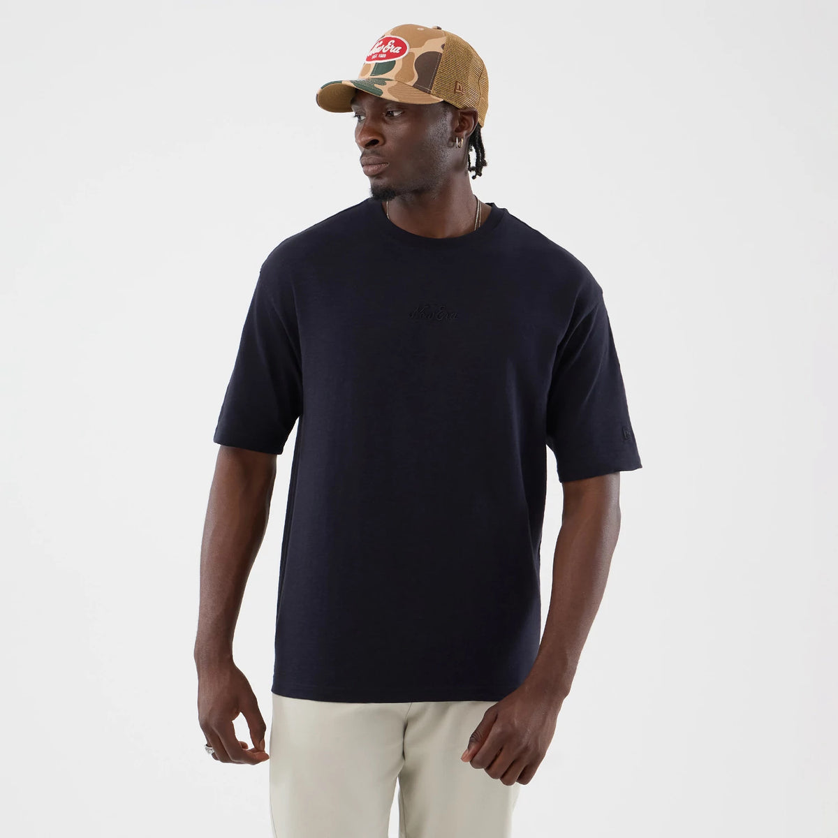 New Era Slub Navy Oversized T-Shirt, front view on a model with a beige camouflage cap, showing a embroidered New Era logo at the centre of the chest, relaxed fit short sleeves and a seamless navy finish.