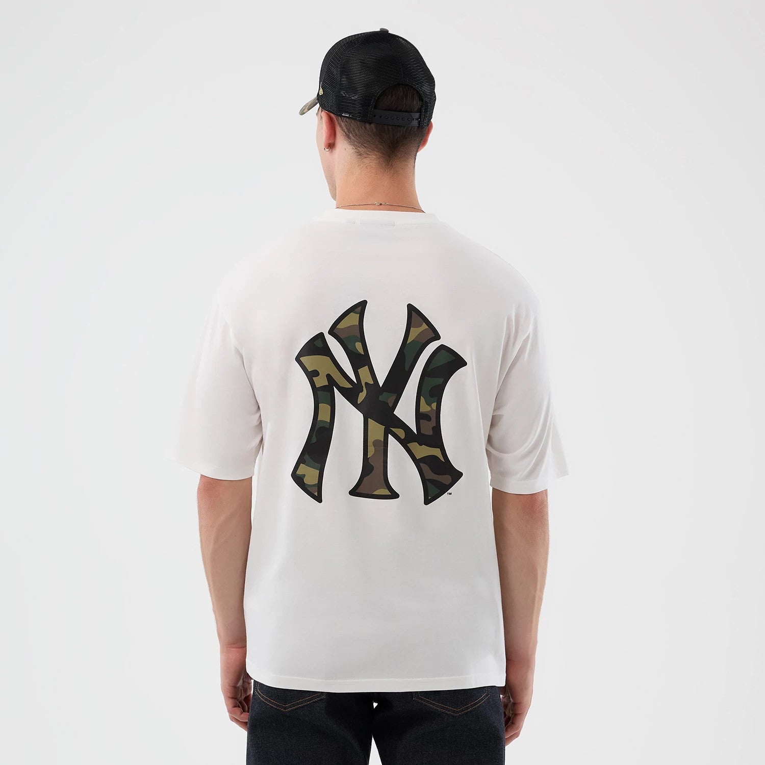 New Era New York Yankees MLB Infill White Oversized T-Shirt, back view on a model wearing a black cap, featuring a large, printed New York Yankees logo in a camouflage design centred on the back of the plain white T-shirt.
