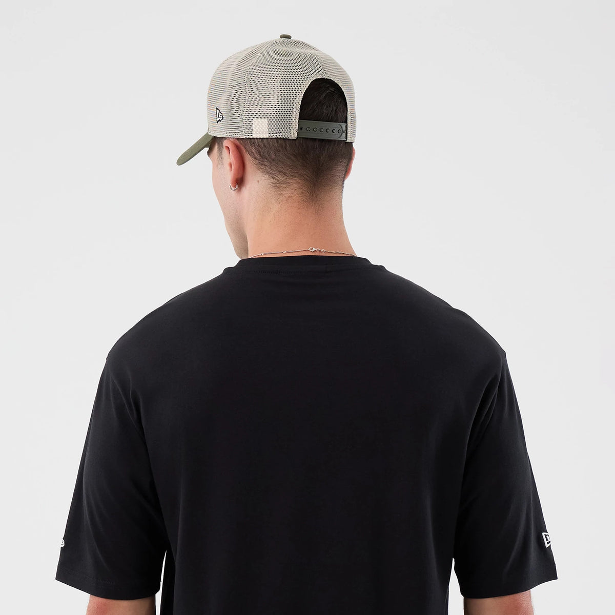 New Era New York Mets MLB Icon Graphic Black T-Shirt, back view on a model wearing a light-coloured cap, showcasing a plain black back with a small embroidered New Era logo on the right sleeve and a round neckline.