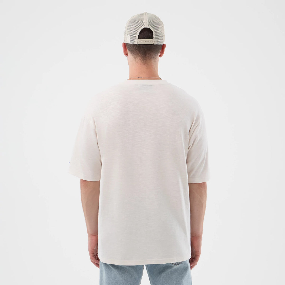 New Era New York Yankees MLB Slub Open White Oversized T-Shirt, back view on a model showcasing the plain white oversized fit with short sleeves, a embroidered logo detail on the sleeve, and worn with a casual light-coloured cap and jeans.
