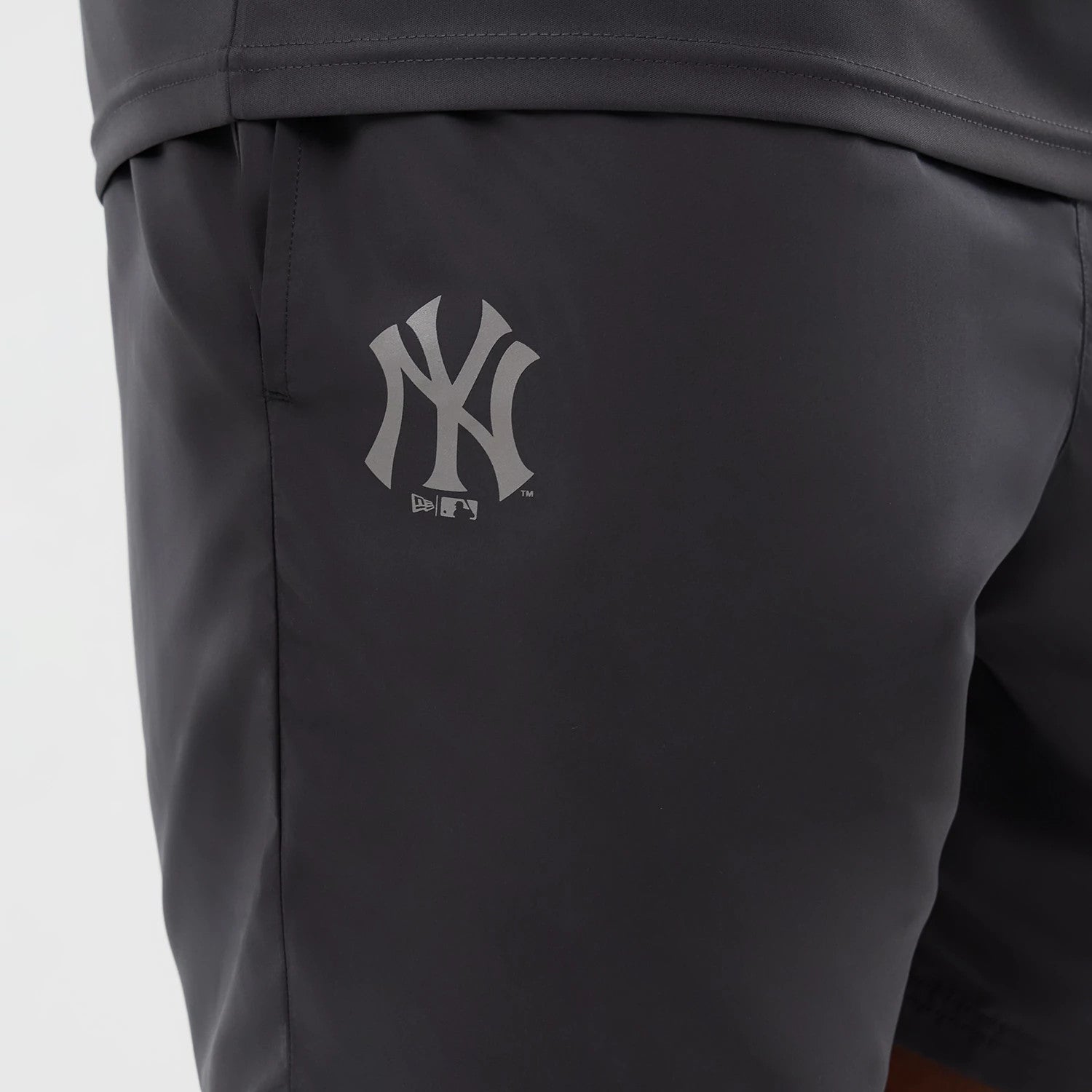 New Era New York Yankees MLB Core Plus Dark Grey Shorts, side view featuring a printed New York Yankees logo on the upper leg, a dark grey finish, and an elasticated waistband at the top of the shorts.