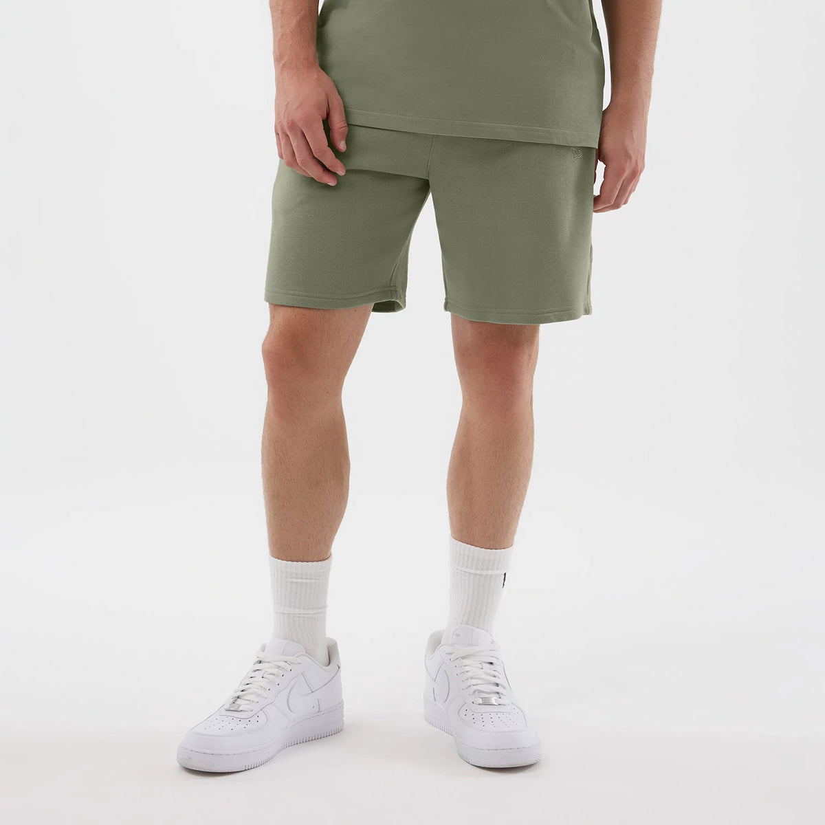 New Era Chicago Bulls NBA League Essential Pastel Green Shorts, front view on a model wearing white trainers and socks, showing knee-length green shorts with a simple straight hem, and a embossed New Era logo near the left pocket.