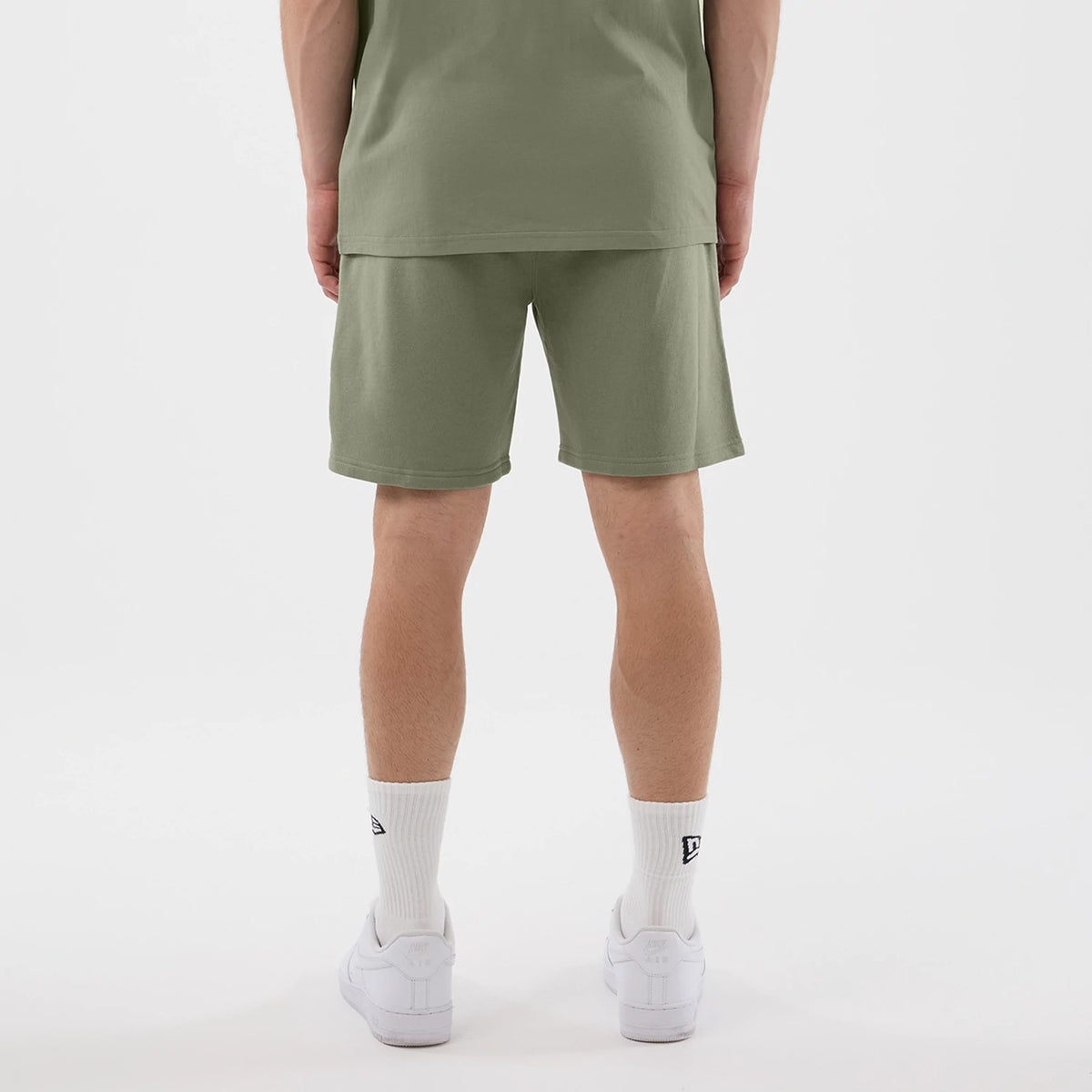 New Era Chicago Bulls NBA League Essential Pastel Green Shorts, back view on a model styled with a matching green top, showcasing the pastel green fabric and the straight hem sitting above the knee for a casual look.