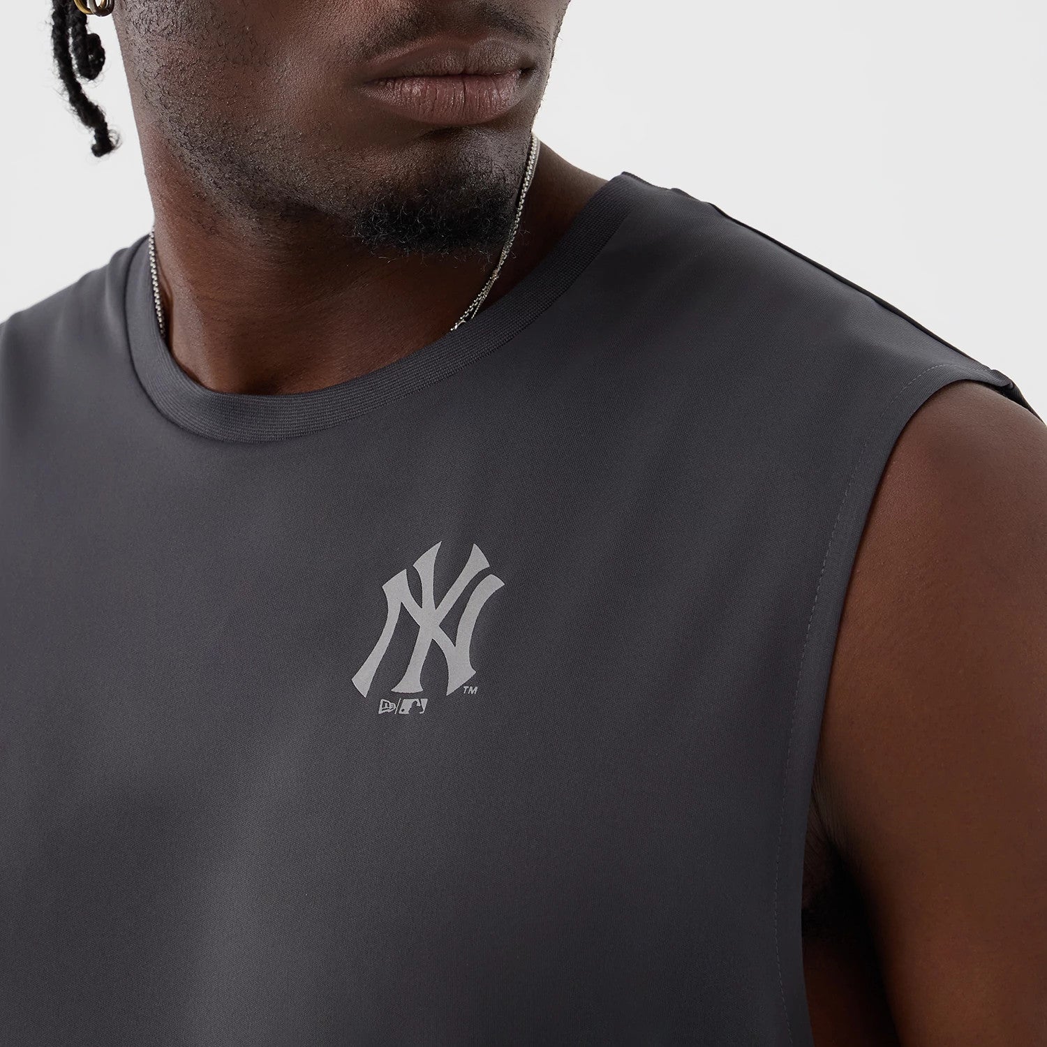 New Era New York Yankees MLB Core Plus Dark Grey Vest, front view on a model displaying the white printed NY logo on the left chest, sleeveless design with wide armholes and a dark grey fabric.