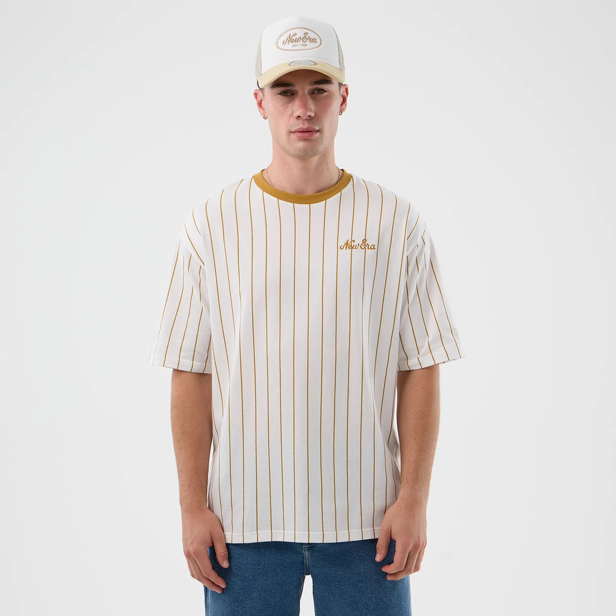 New Era Pinstripe White Oversized T-Shirt, front view on a model wearing a matching cap, featuring thin vertical stripes and a contrasting mustard collar, with an embroidered New Era logo on the left chest area.