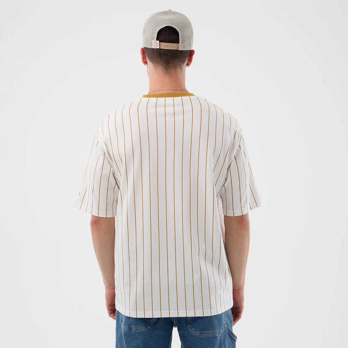 New Era Pinstripe White Oversized T-Shirt, back view on a model wearing blue jeans and a neutral cap, highlighting the vertical pinstripe pattern in a contrasting colour against the white fabric, and a plain neckline without any logos.