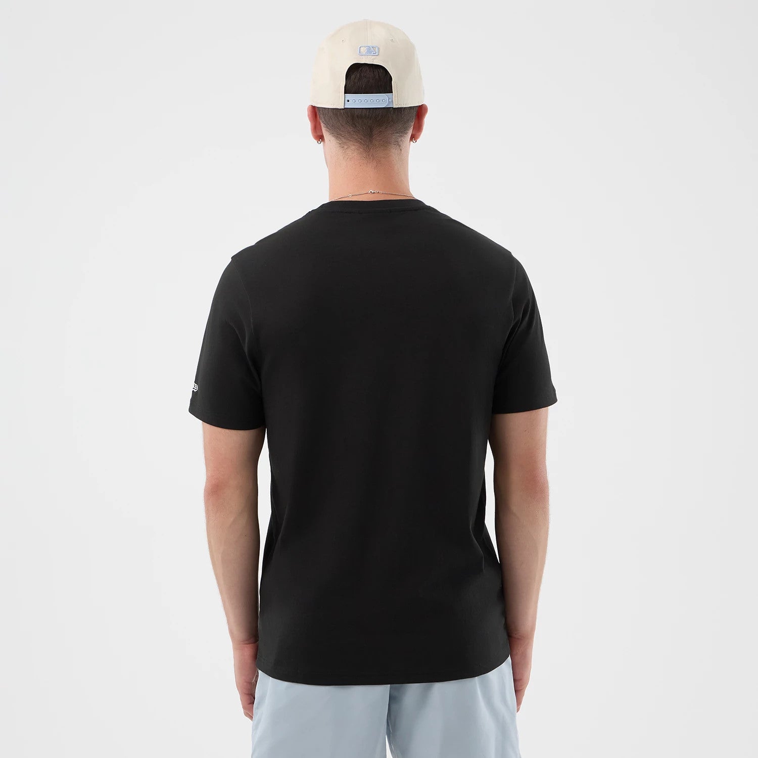 The model is wearing this New Era Logo Graphic T-Shirt in black. 2