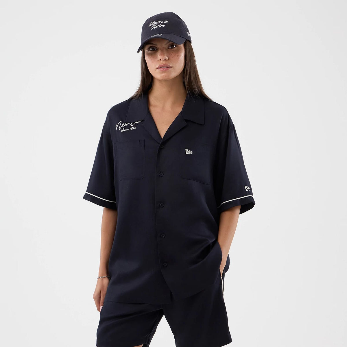 The model is wearing this New Era Graphic Revere Short Sleeve Shirt in navy. 4