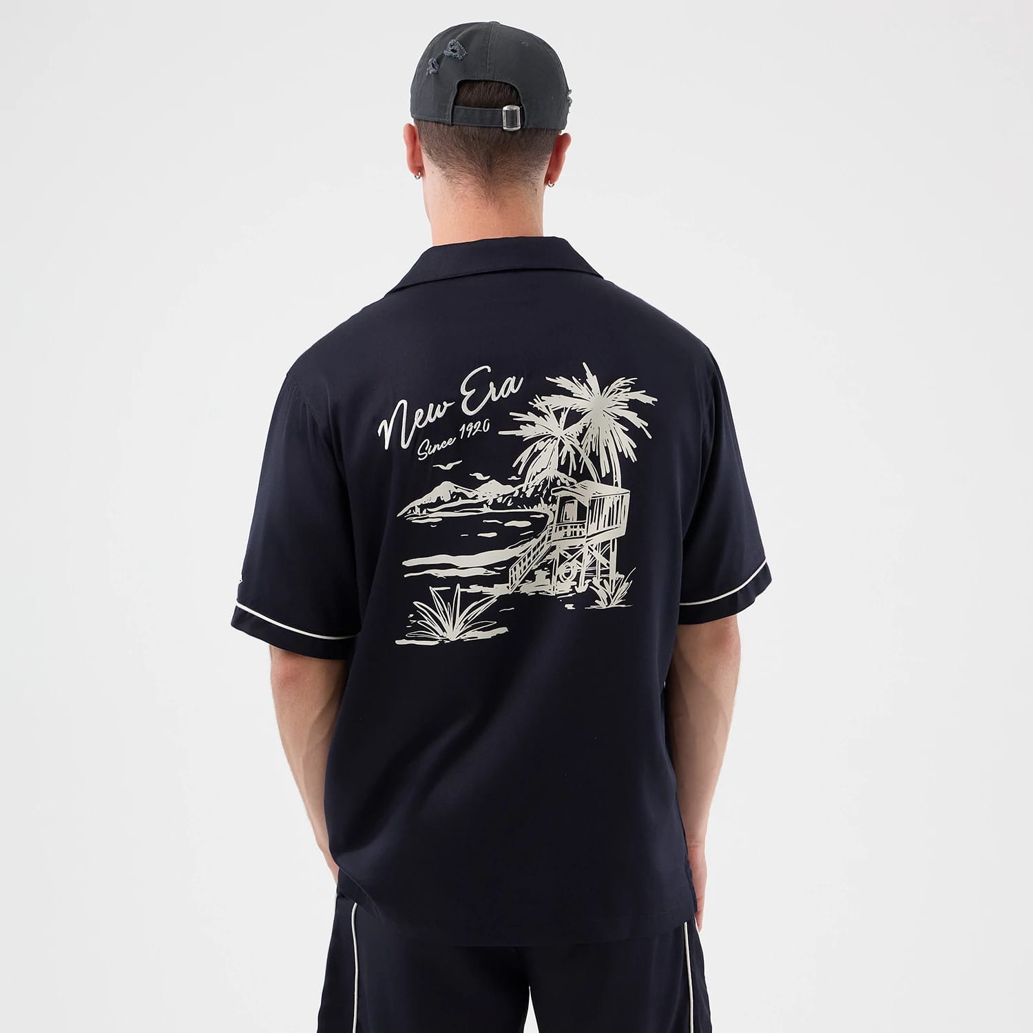 The model is wearing this New Era Graphic Revere Short Sleeve Shirt in navy. 2