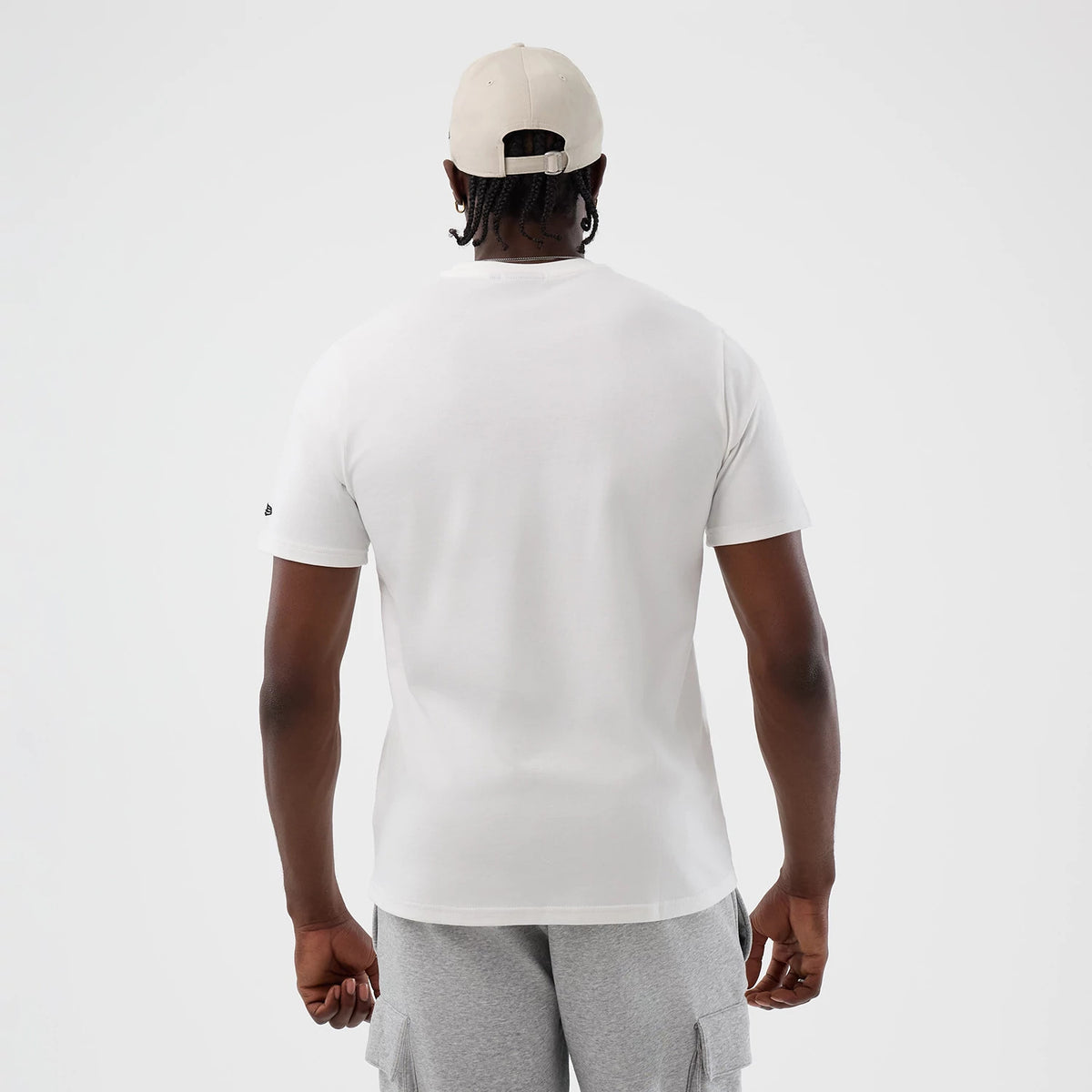 New Era LA Lakers NBA Beach Graphic White T-Shirt, back view on a model paired with grey shorts and a beige cap, showing a clean white finish with a small embroidered New Era logo on the left sleeve.