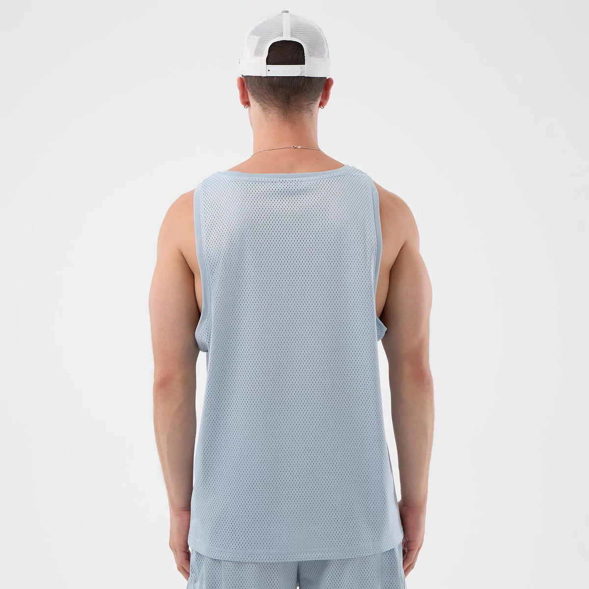 New Era Mesh Pastel Blue Oversized Tank Top, back view on a model wearing a white cap, showing the lightweight mesh fabric and loose fit that extends slightly below the waist, enhancing comfort and casual street style.
