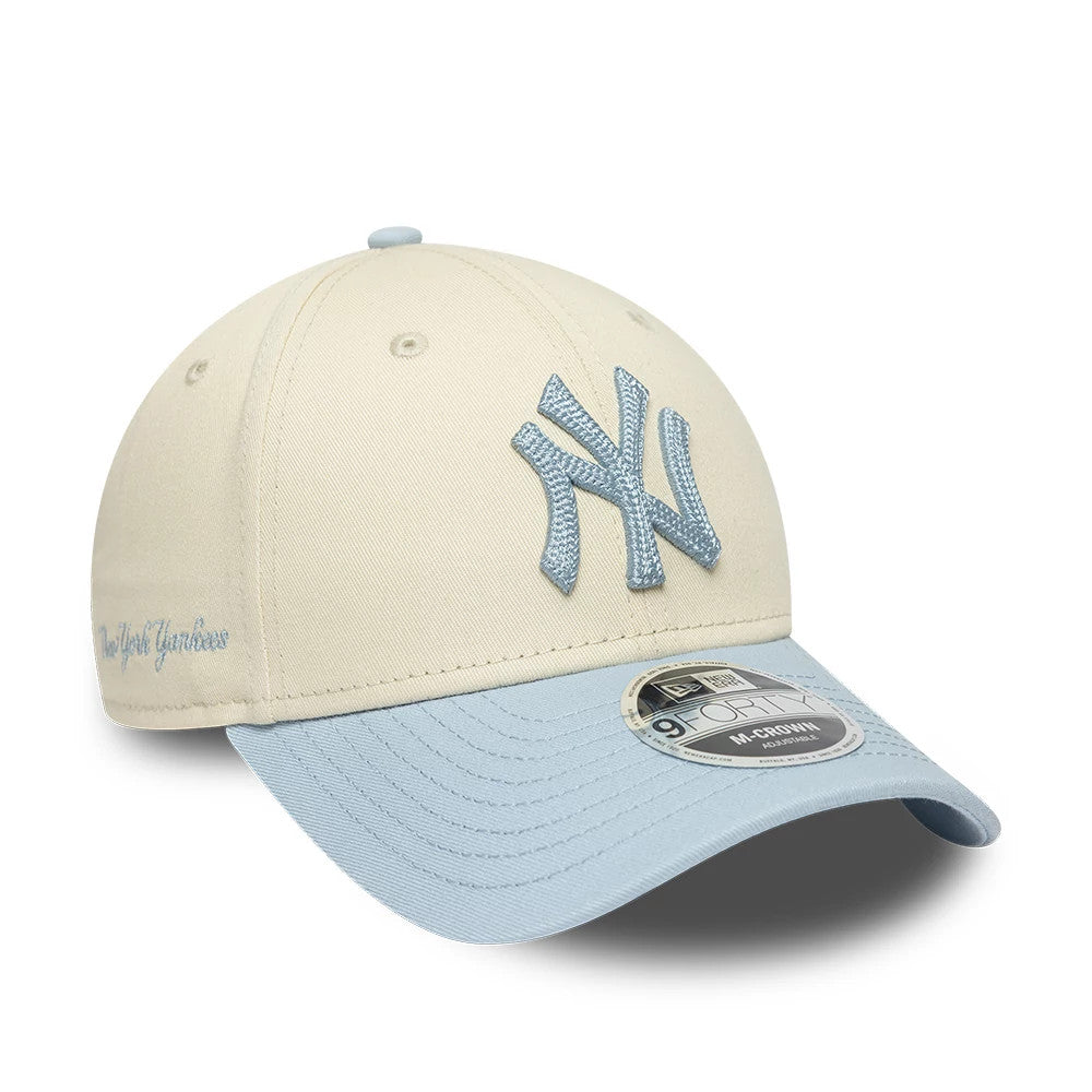 New York Yankees MLB Side Script Cream New Era 9FORTY M-Crown Adjustable Cap, three-quarter view showing a light blue embroidered NY logo on the cream crown, matching visor with a 9FORTY size sticker, and side script logo in light blue.