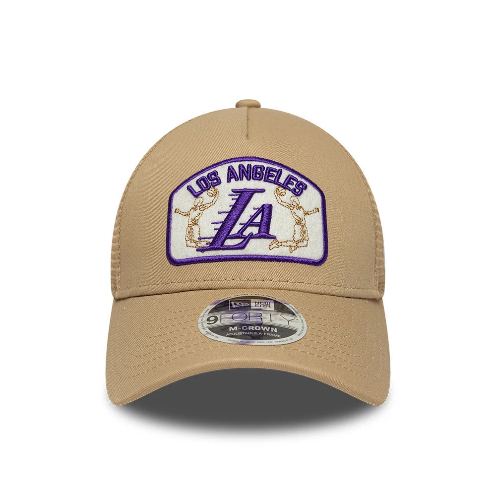 LA Lakers NBA Beige New Era 9FORTY M-Crown A-Frame Trucker Adjustable Cap, front view showing a purple and gold embroidered Los Angeles Lakers logo patch on the beige crown, with a matching beige curved visor and 9FORTY size sticker.