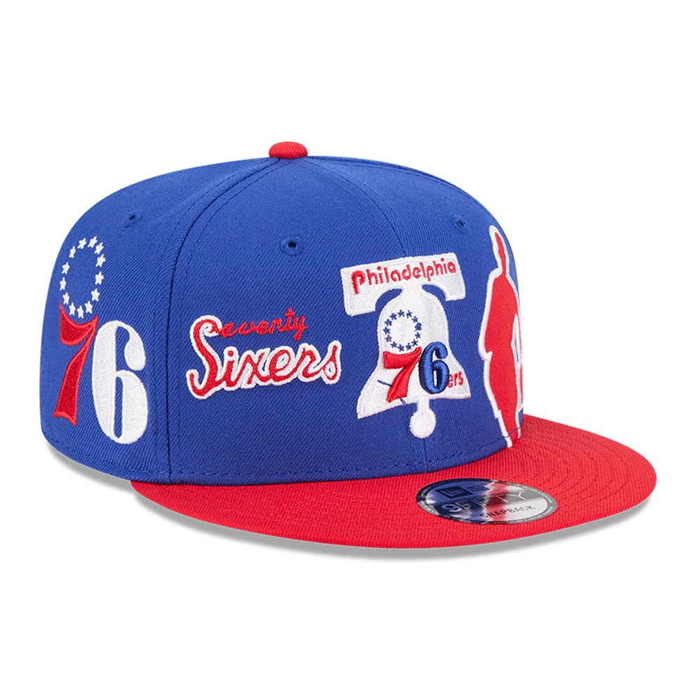 76ers NBA Hardwood Classic ASG Blue New Era 9FIFTY Snapback Adjustable Cap, front three-quarter view showing multiple embroidered logos on the blue crown, a red and blue Sixers graphic, a red visor, and the 9FIFTY size sticker on the visor.