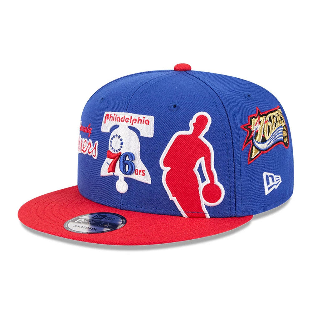76ers NBA Hardwood Classic ASG Blue New Era 9FIFTY Snapback Adjustable Cap, three-quarter view showing the red visor, multiple embroidered logos including a basketball silhouette and team graphics on the blue crown, with a 9FIFTY size sticker.