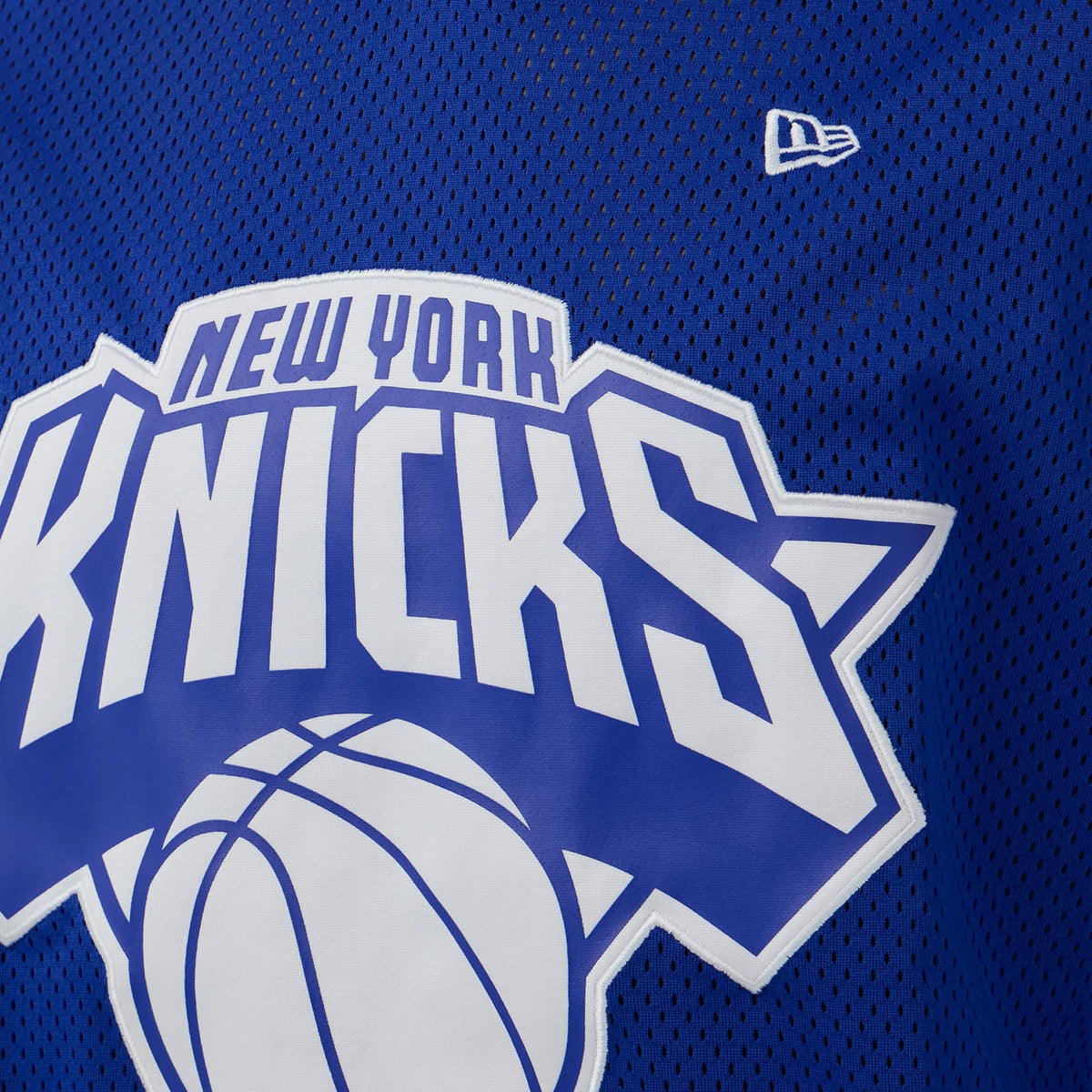 New Era New York Knicks NBA Mesh Blue Oversized T-Shirt, front view showing a large white printed New York Knicks logo with a stylised basketball across the chest, set against a blue mesh fabric.