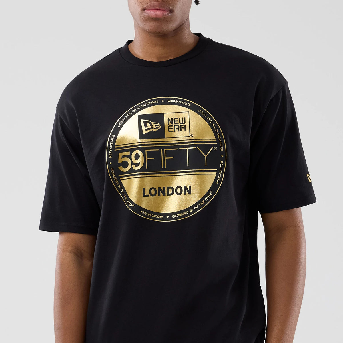 New Era Sticker London Black Oversized T-Shirt, front view showing a large gold printed 59FIFTY badge with London text on the chest, a New Era logo on the left sleeve, and the relaxed fit on a model.