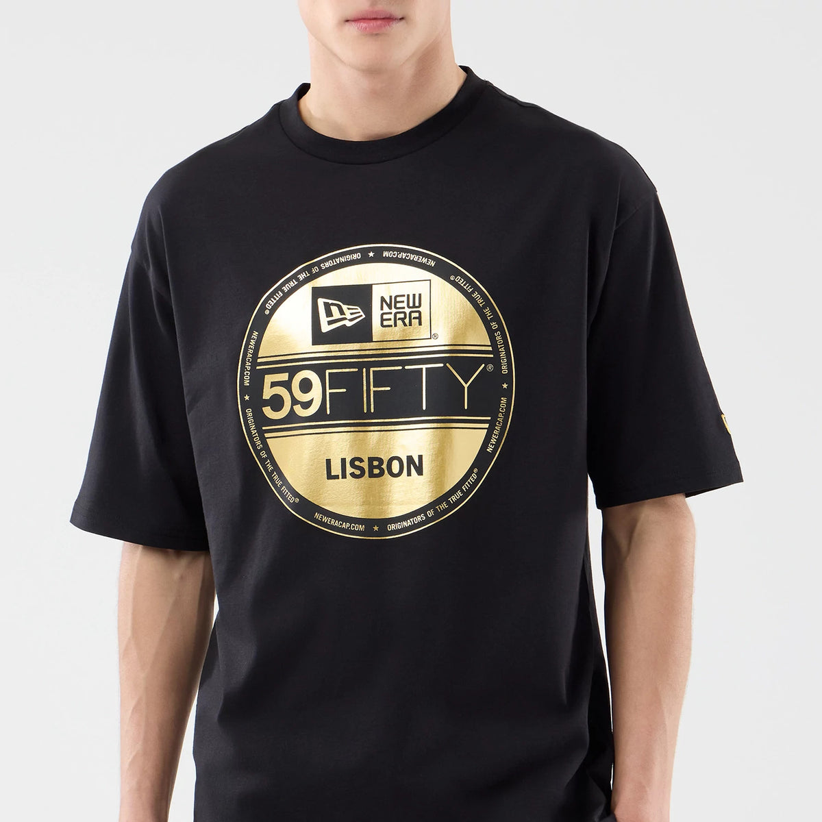 New Era Sticker Lisbon Black Oversized T-Shirt, front view on-model displaying a prominent large gold printed graphic featuring the New Era logo, 59FIFTY and Lisbon text across the chest, with a small logo on the left sleeve.