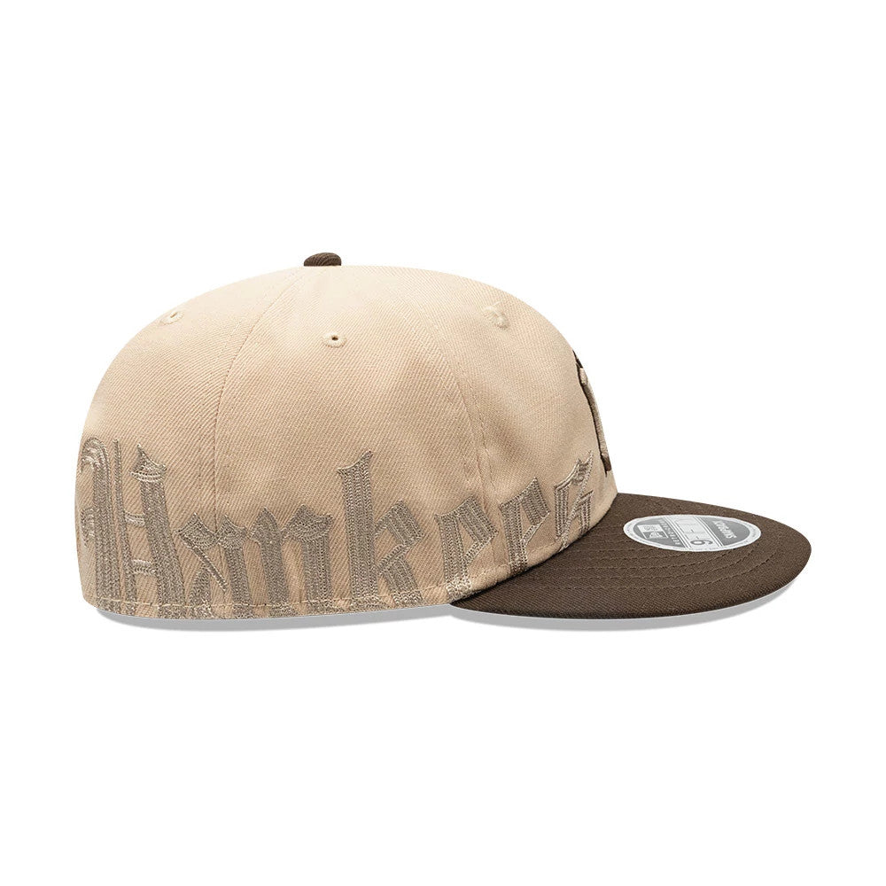 New York Yankees MLB Gothic Script Beige Retro Crown New Era 9FIFTY Cap, side view showing the beige embroidered 'Yankees' script wrapping around the structured crown, with a brown flat visor and a 9FIFTY size sticker on the top.
