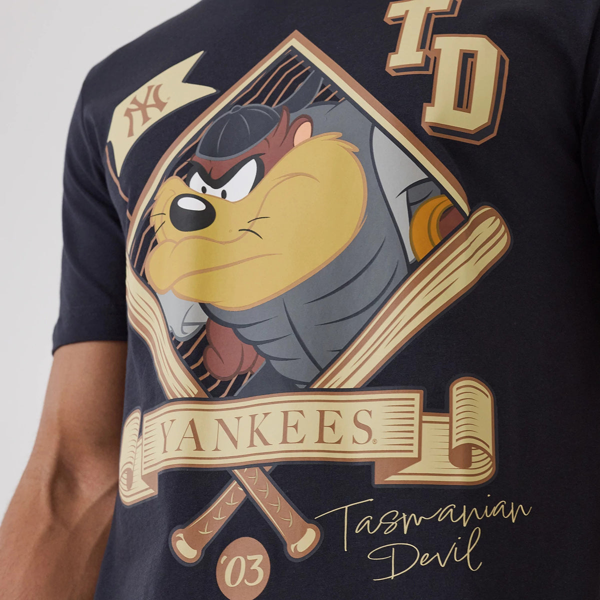 New Era New York Yankees MLB X Looney Tunes Navy T-Shirt, front view showcasing a large printed graphic of the Tasmanian Devil in a baseball uniform, with Yankees branding beneath, a crossed bats emblem, and a yellow NY logo on a small flag above.