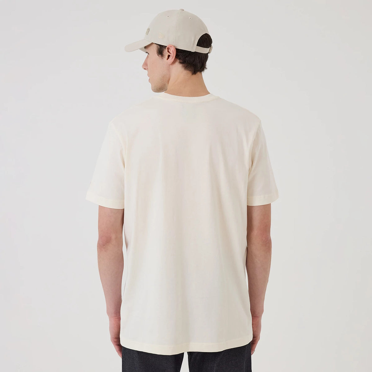 New Era New York Yankees MLB X Looney Tunes Cream T-Shirt, back view on a model with a matching cream cap, highlighting the plain cream back of the t-shirt and short sleeves, providing a clean, minimalist look without graphics or logos.