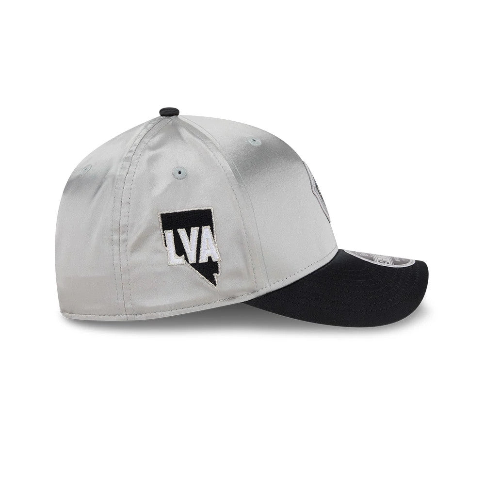 Las Vegas Aces WNBA Draft 2026 Silver New Era 9FORTY M-Crown Adjustable Cap, side view showing the black LVA logo on the silver structured crown with eyelets, a black curved visor with a 9FORTY size sticker, and the top button also in black.